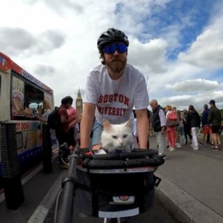 トラヴィスさんといっしょに自転車でウェストミンスター橋の上を通過するシグリッドちゃん